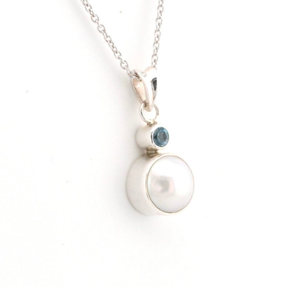 Necklace with a pearl pendant and blue gemstone on a white background