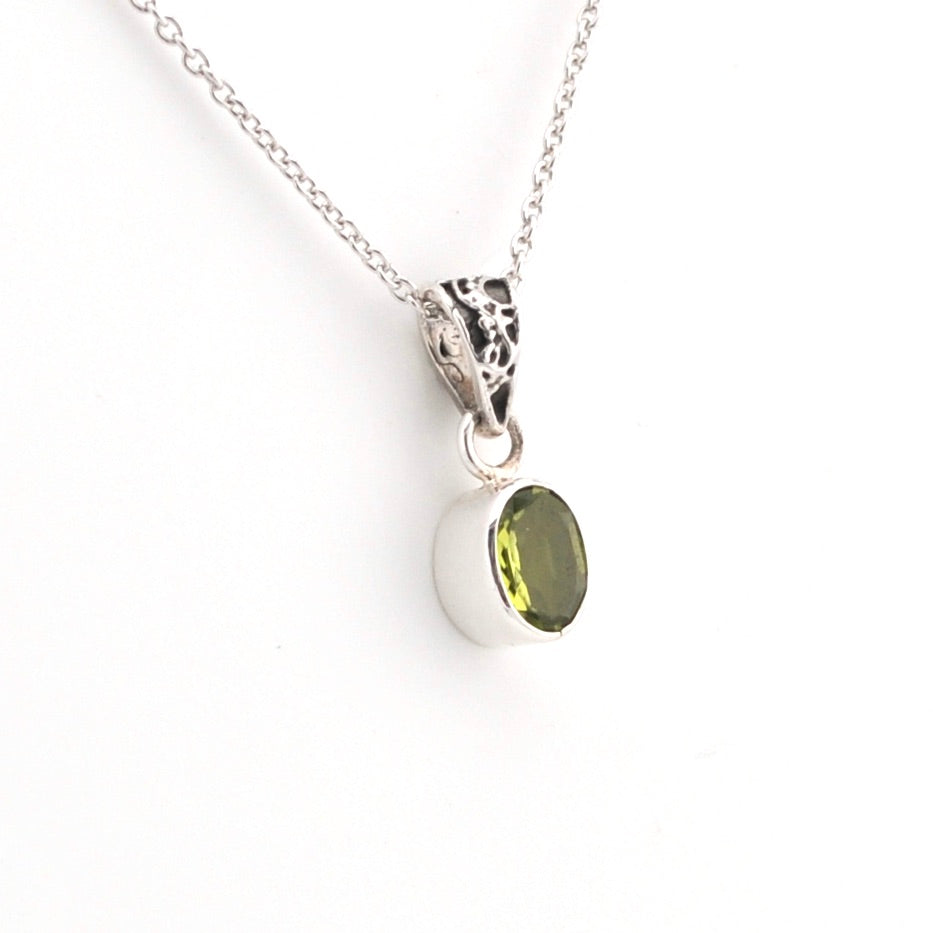 Silver necklace with a green gemstone pendant on a white background
