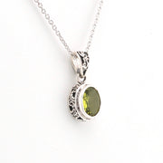 Silver pendant with a green gemstone on a white background