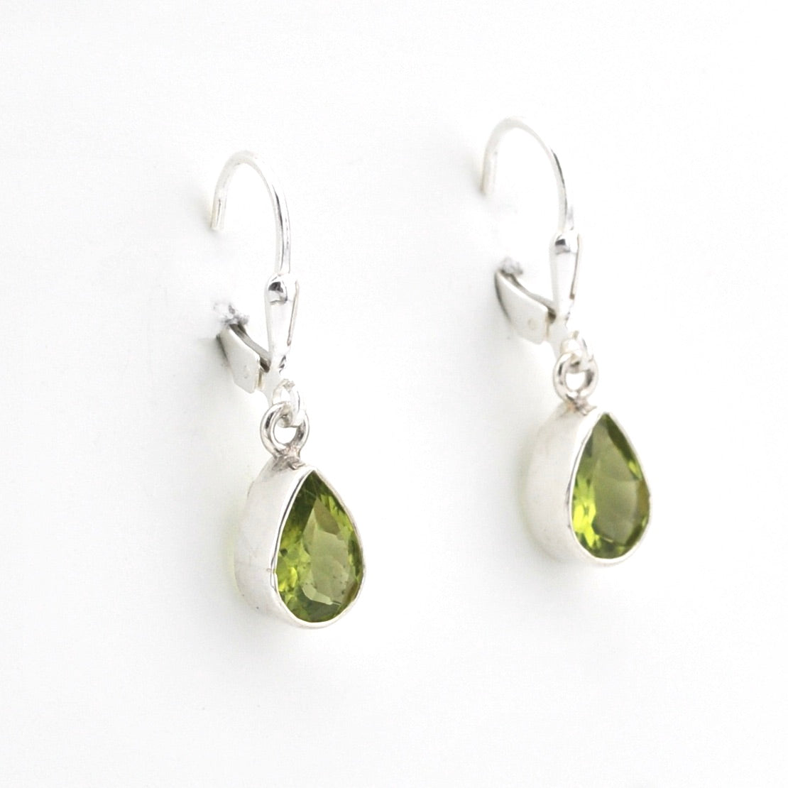 Silver earrings with green teardrop stones on a white background