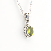 Silver pendant with a green gemstone on a white background