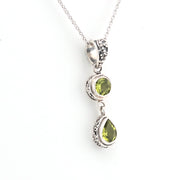 Silver necklace with green gemstone pendant on a white background