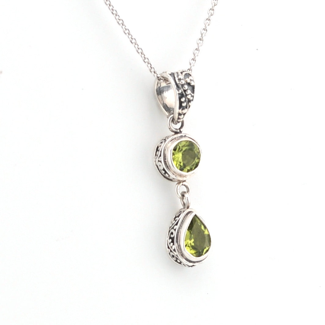 Silver necklace with green gemstone pendant on a white background