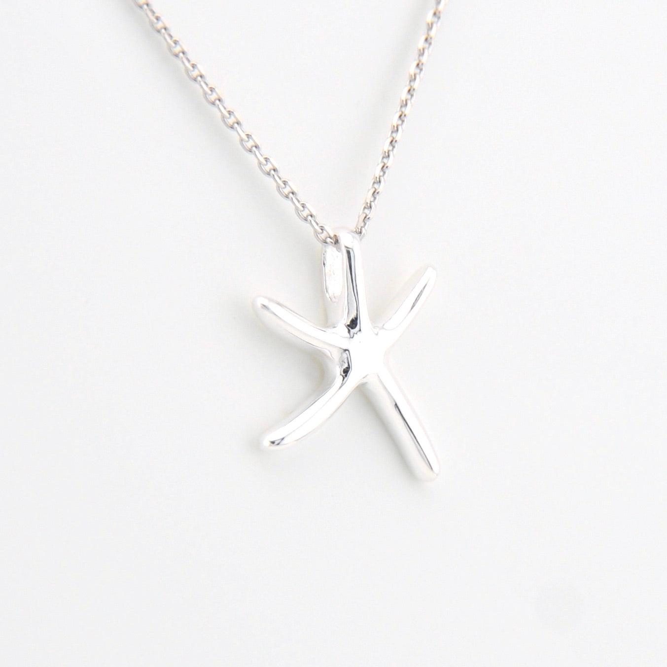 Silver starfish pendant necklace on a white background