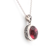 Silver pendant with a red gemstone on a white background