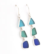 Pair of earrings with blue and green triangular glass on a white background