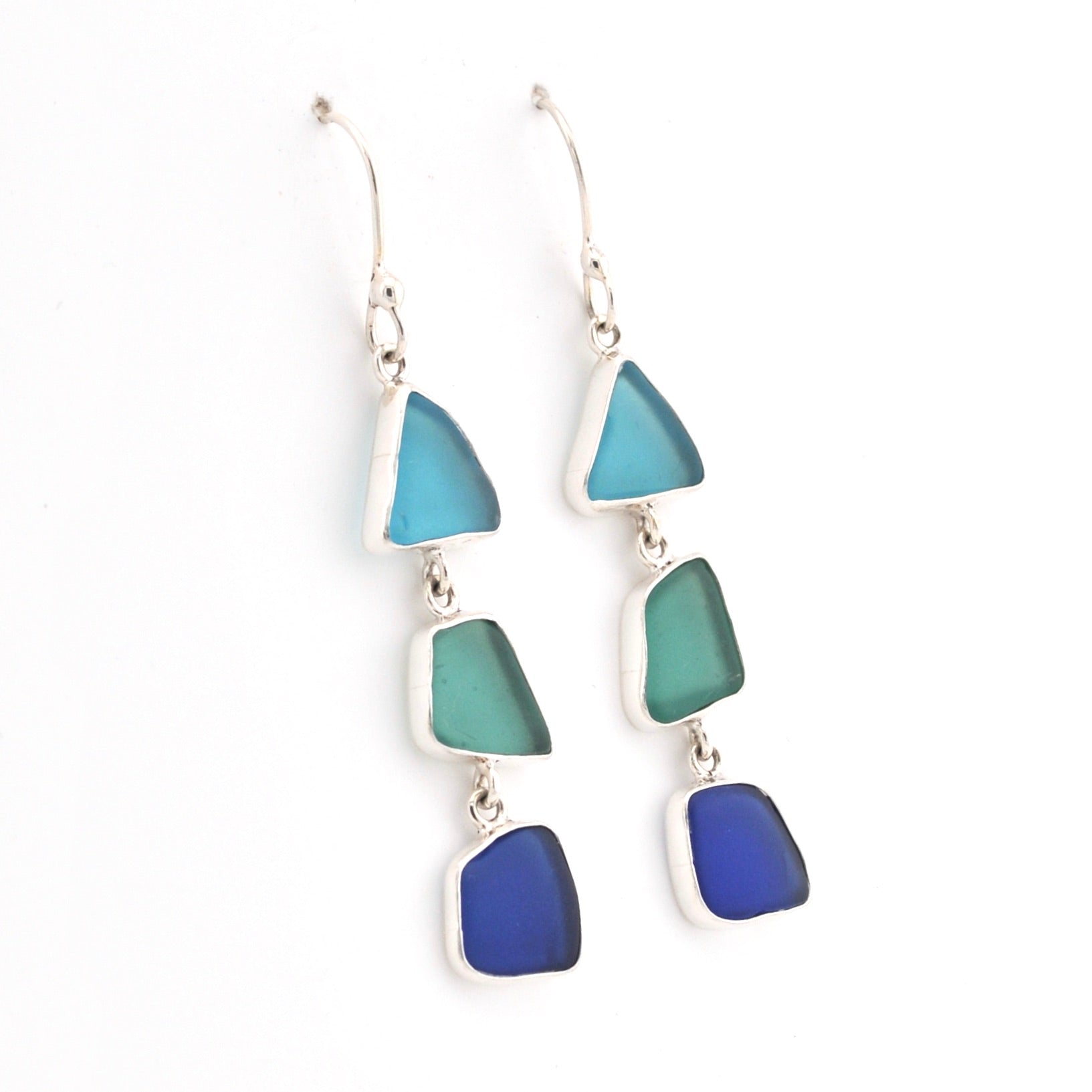 Pair of earrings with blue and green triangular glass on a white background
