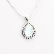 Teardrop-shaped pendant with a white stone on a white background