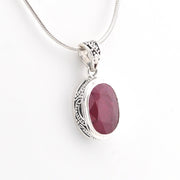 Silver pendant with a red gemstone on a white background
