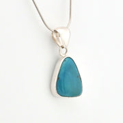 Turquoise pendant on a silver chain against a white background