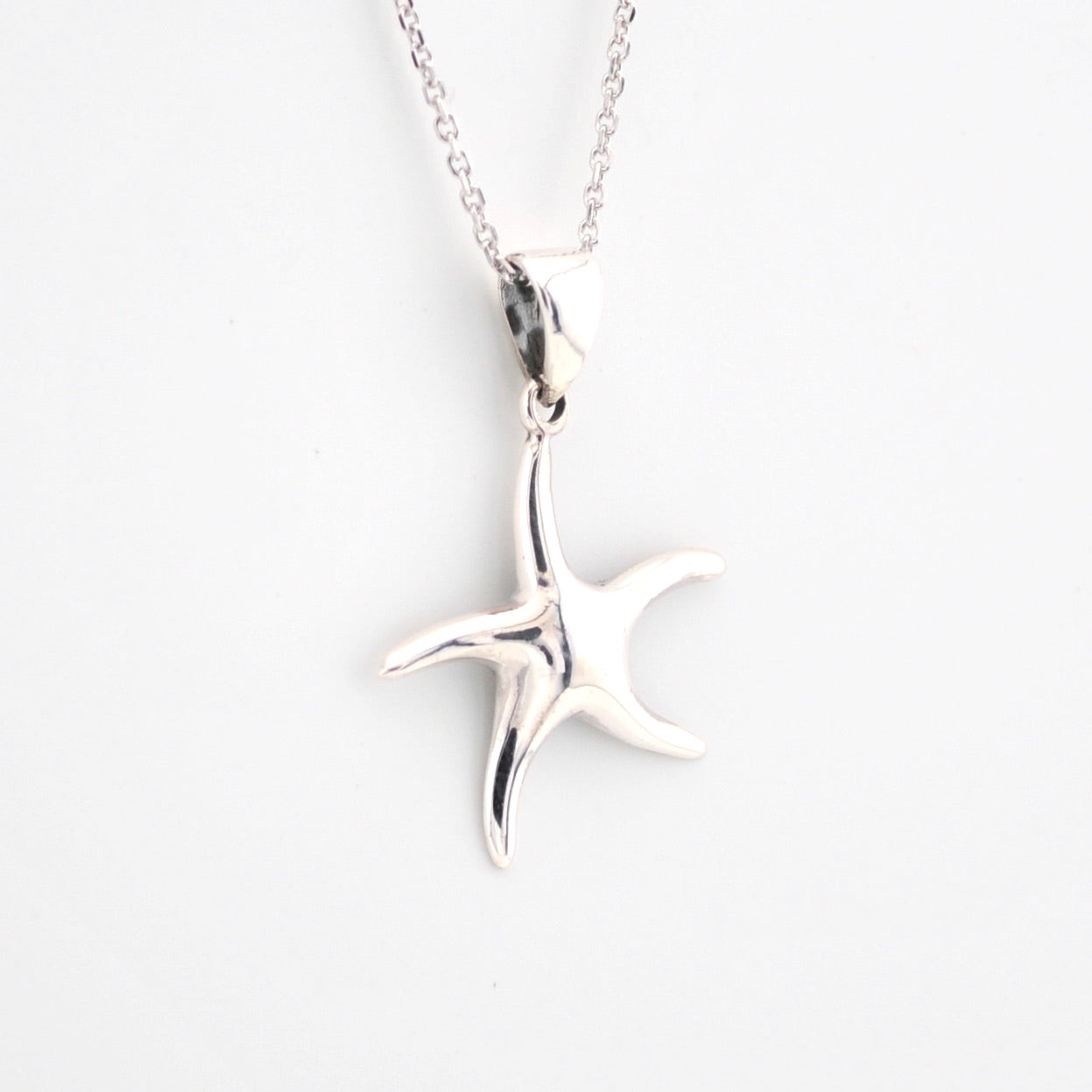 Silver starfish pendant on a chain against a white background