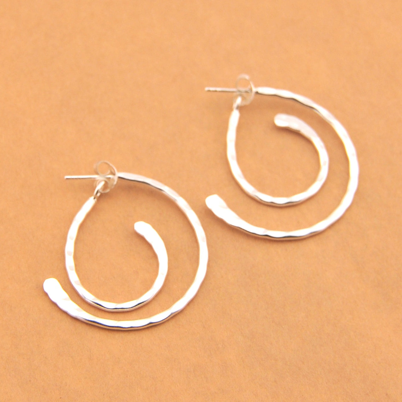 Pair of silver hoop earrings on a beige background