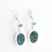 Pair of earrings with blue stone drops on a white background
