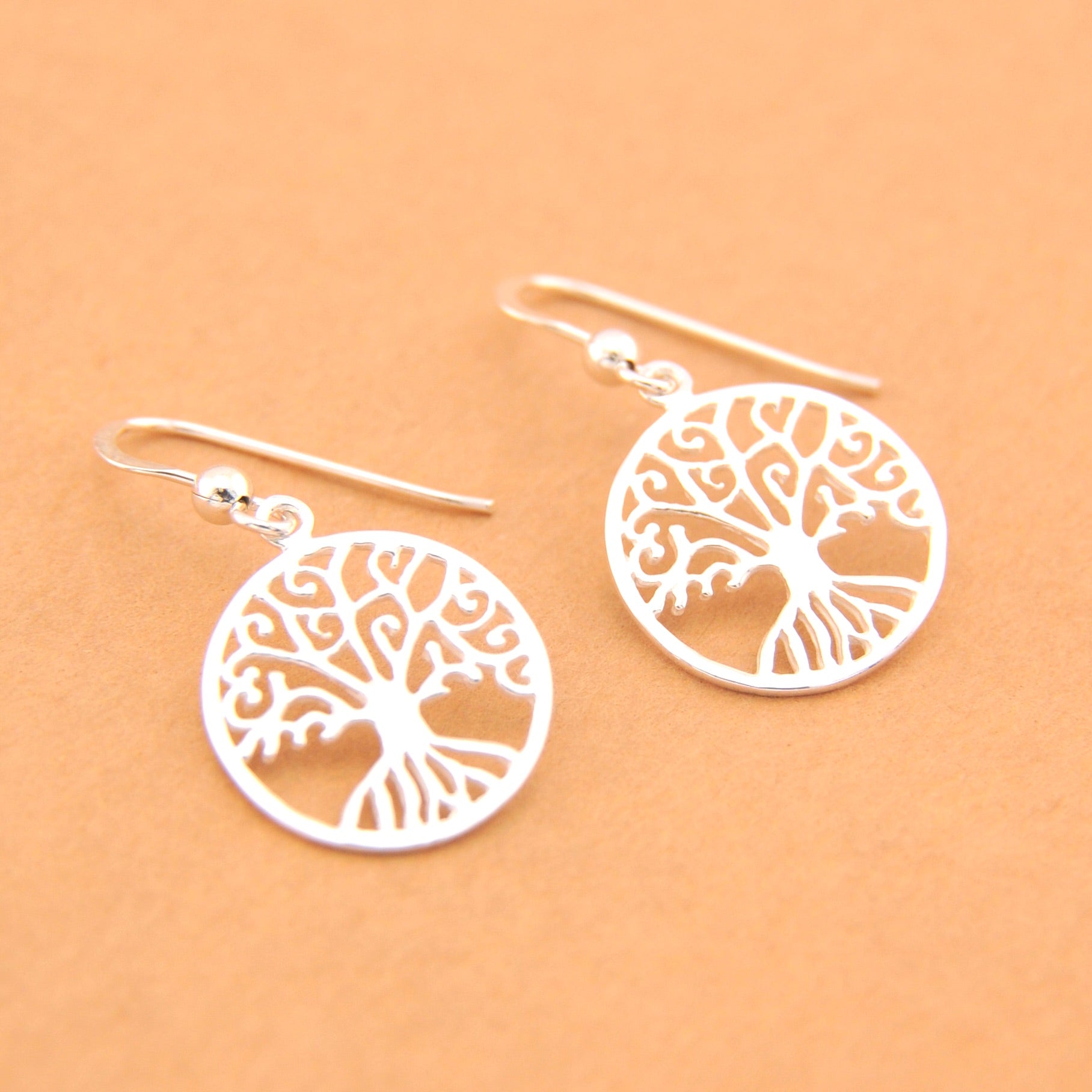 Silver tree-of-life earrings on a beige background