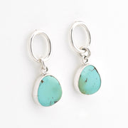 Turquoise stone earrings on silver hooks against a white background