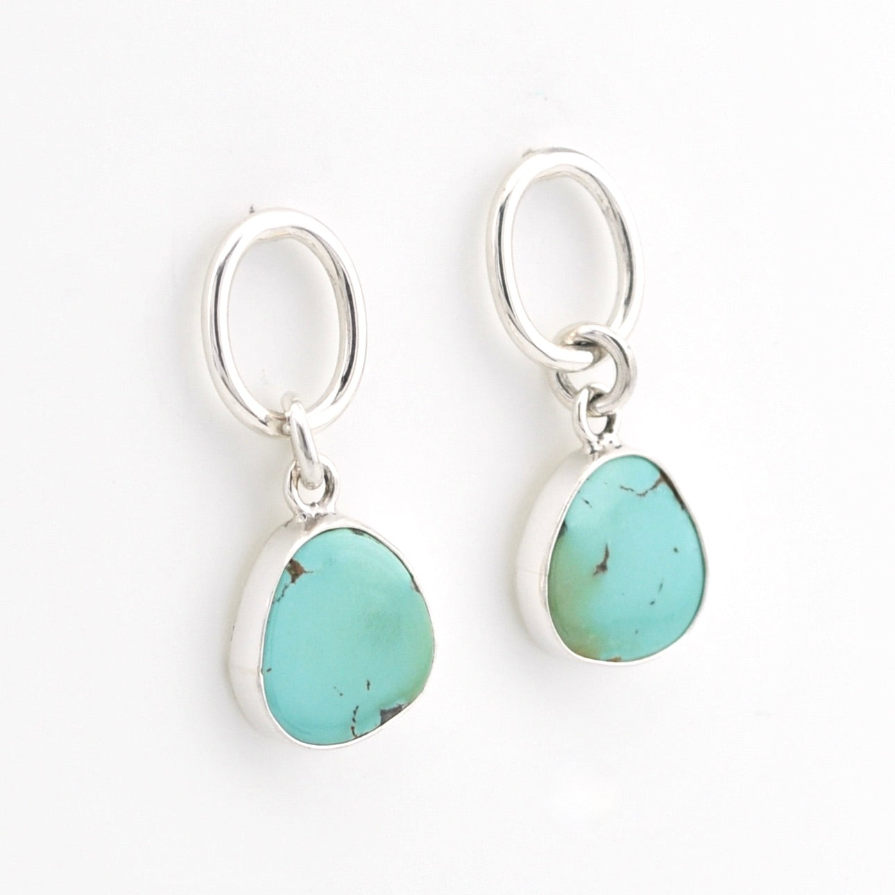 Turquoise stone earrings on silver hooks against a white background
