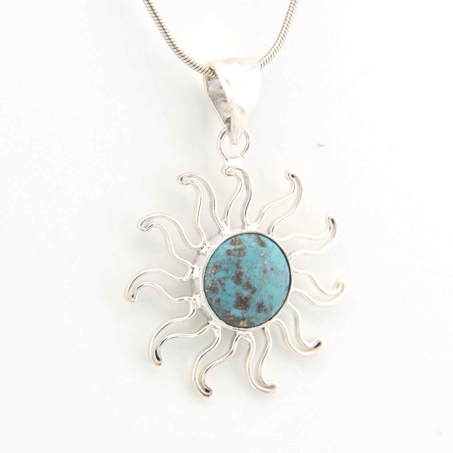 Silver sun-shaped pendant with a turquoise center on a white background