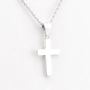 Silver cross pendant on a chain against a white background