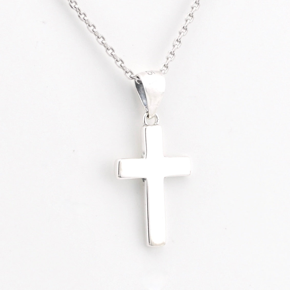 Silver cross pendant on a chain against a white background