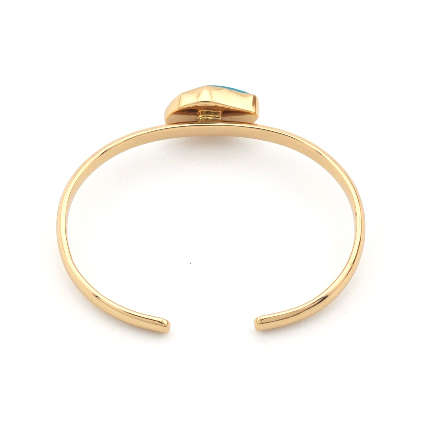 Gold bracelet with a small gemstone on a white background