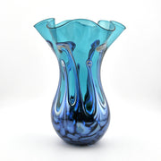 Blue glass vase with a wavy design on a white background