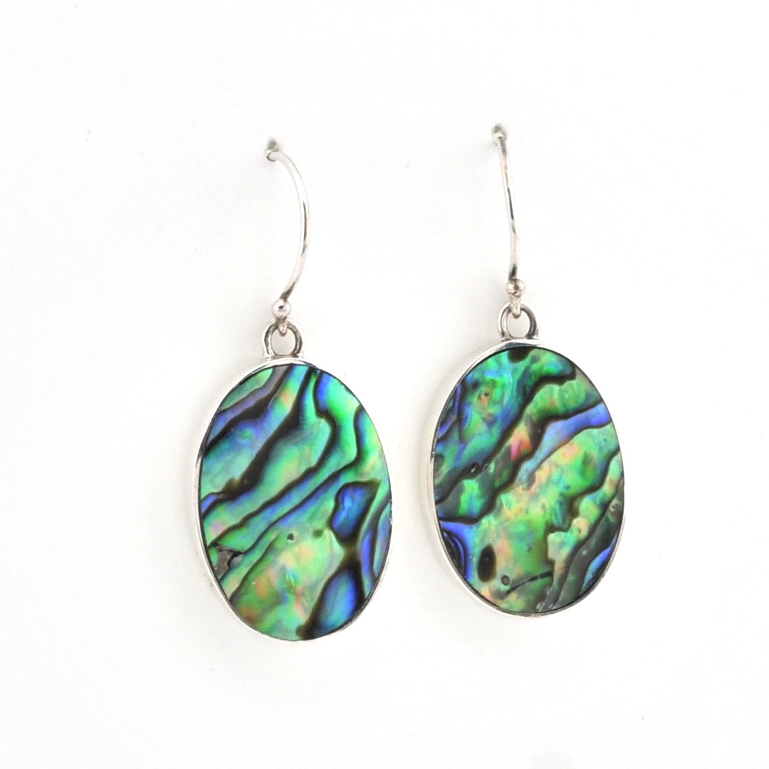 A pair of silver drop earrings featuring oval abalone shell inlays with a vibrant green, blue, and purple iridescent pattern, shown against a plain white background.