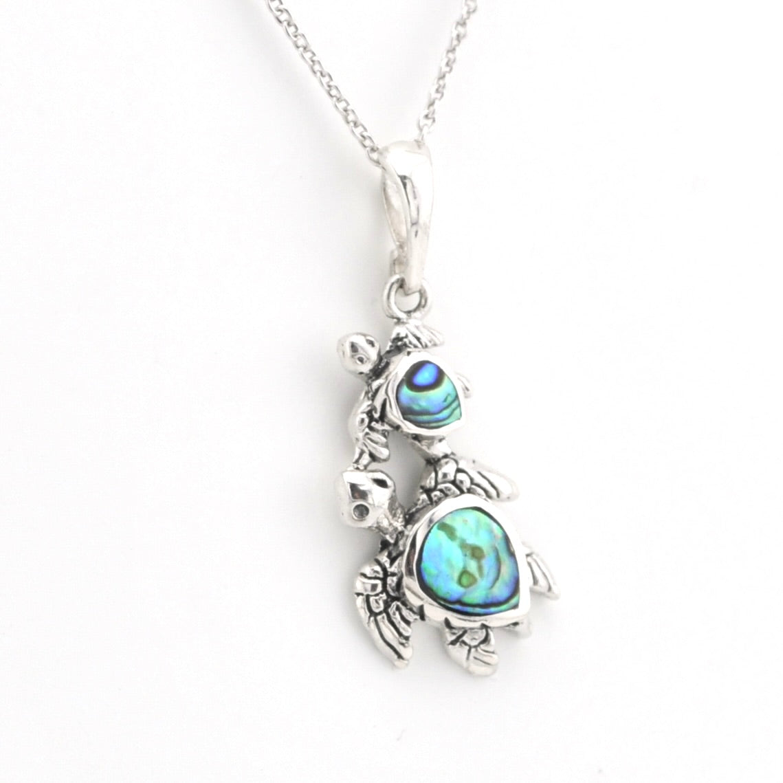 A sterling silver turtle pendant necklace featuring iridescent blue-green abalone shell inlays on the head and shell, shown on a white background.
