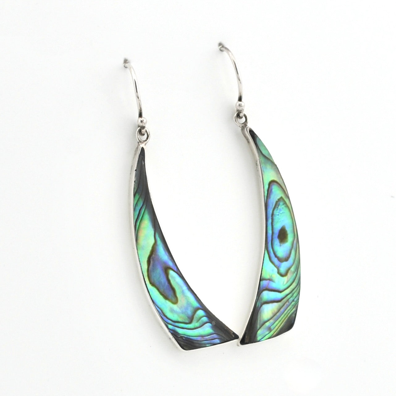 A pair of silver dangle earrings with curved, fan-shaped abalone shell inlays showing iridescent green, blue, and purple patterns, set against a plain white background.