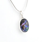 A silver chain necklace with an oval pendant featuring a dark abalone shell inlay with iridescent blue, purple, and green hues, set against a plain white background.
