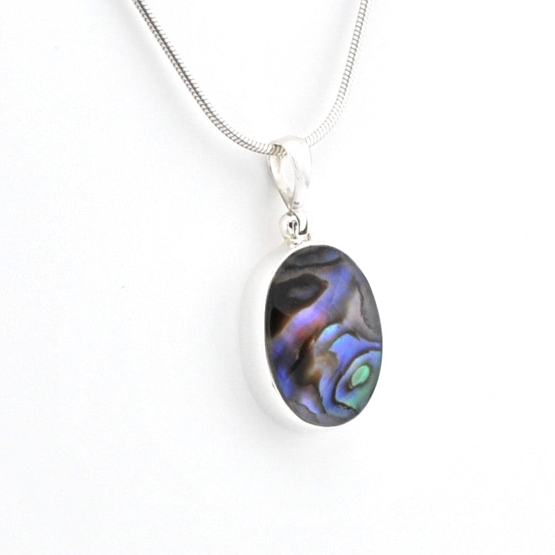 A silver chain necklace with an oval pendant featuring a dark abalone shell inlay with iridescent blue, purple, and green hues, set against a plain white background.