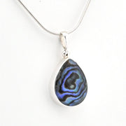 A silver teardrop pendant necklace featuring a polished abalone shell inlay with iridescent blue, purple, and black swirls, suspended from a delicate silver snake chain against a plain white background.
