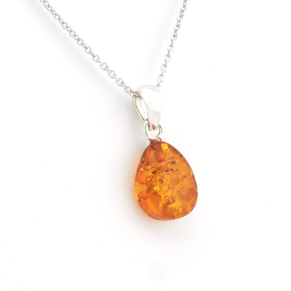 A teardrop-shaped amber pendant necklace on a delicate silver chain, set against a plain white background.