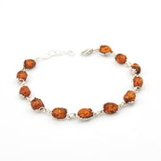 A silver-tone beaded bracelet featuring seven polished oval amber brown gemstones, displayed on a clean white background.