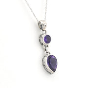 A silver pendant necklace featuring a teardrop-shaped purple gemstone and a smaller oval purple gemstone, displayed on a clean white background.