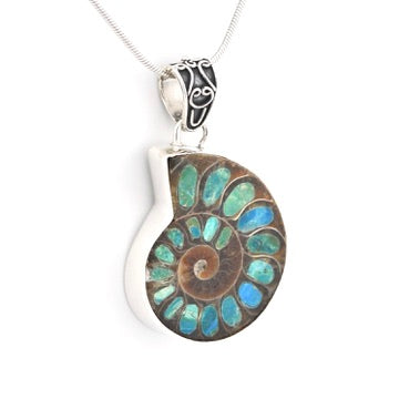 A silver pendant necklace featuring a polished spiral ammonite shell with inlaid blue-green opal stones, suspended from a delicate silver chain against a plain white background.