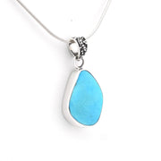 A silver pendant necklace featuring a teardrop-shaped turquoise stone in a polished silver bezel setting, suspended from a silver snake chain against a plain white background.