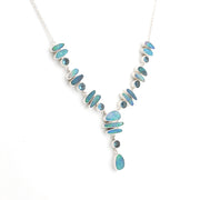 A silver Y-shaped necklace featuring multiple iridescent blue-green stones in oval and teardrop shapes, displayed on a clean white background.