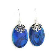 A pair of silver dangle earrings featuring oval blue abalone shell with a silver filigree cap, shown against a plain white background.