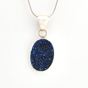 Blue druzy pendant on a silver chain against a white background