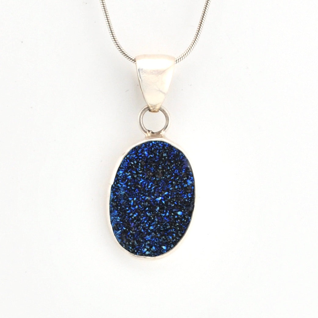 Blue druzy pendant on a silver chain against a white background
