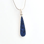 Blue teardrop pendant on a silver chain against a white background