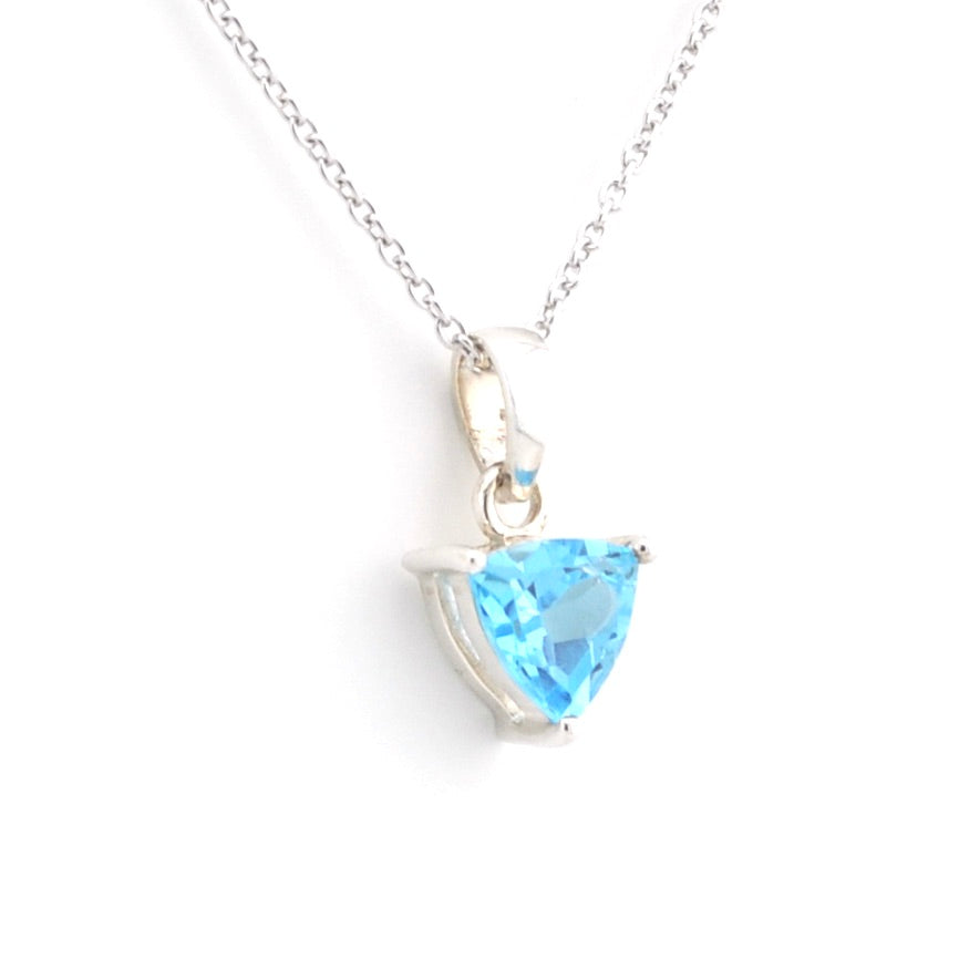 A silver pendant necklace featuring a faceted light blue triangular gemstone in a prong setting, suspended from a delicate silver chain against a plain white background.
