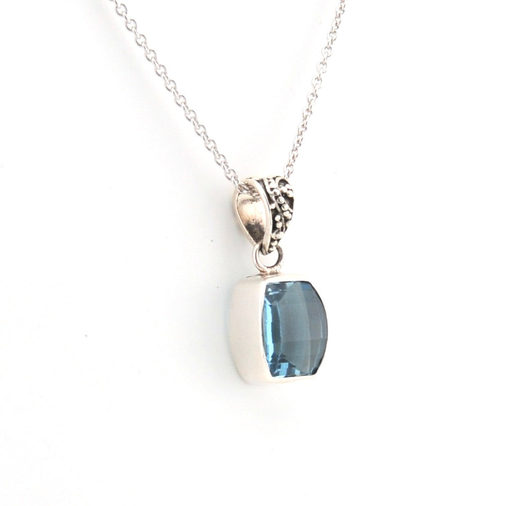 Silver necklace with a blue gemstone pendant on a white background