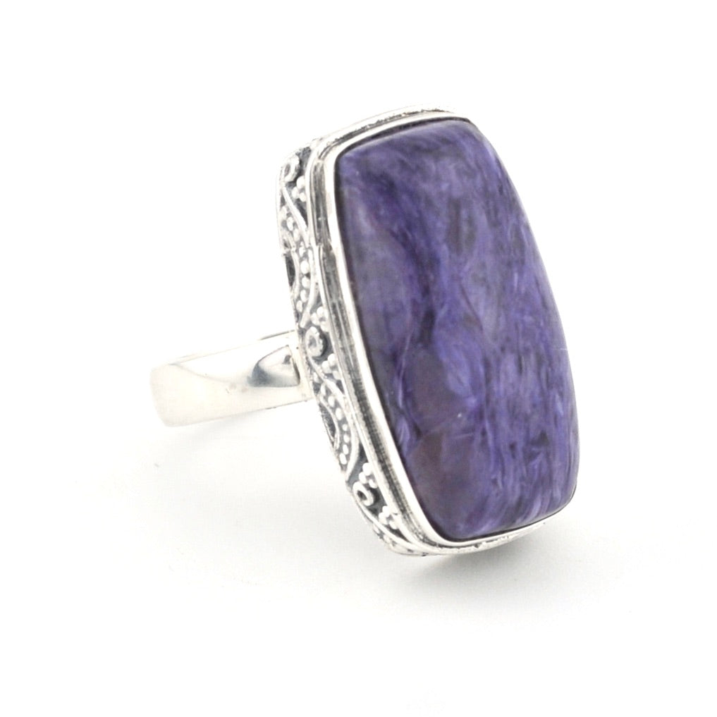 A silver ring featuring a large, rectangular purple stone with natural marbled patterns, set in an ornate silver bezel with a polished silver band, shown on a white background.