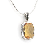 A silver pendant necklace featuring a faceted, rectangular golden-yellow gemstone in a silver bezel setting, suspended from a silver snake chain against a white background.