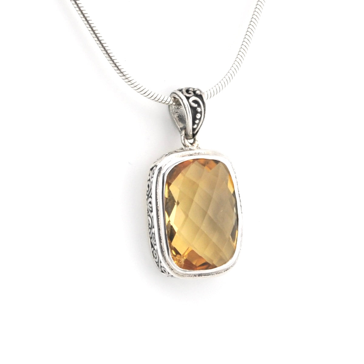 A silver pendant necklace featuring a faceted, rectangular golden-yellow gemstone in a silver bezel setting, suspended from a silver snake chain against a white background.