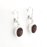 A pair of silver leverback drop earrings featuring oval dark brown gemstones, displayed on a clean white background.
