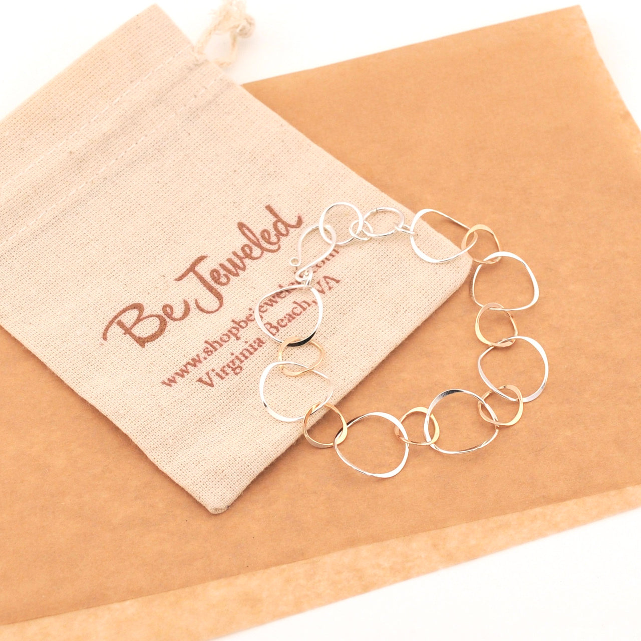 Silver bracelet on a beige fabric with 'Be Jeweled' jewelry bag