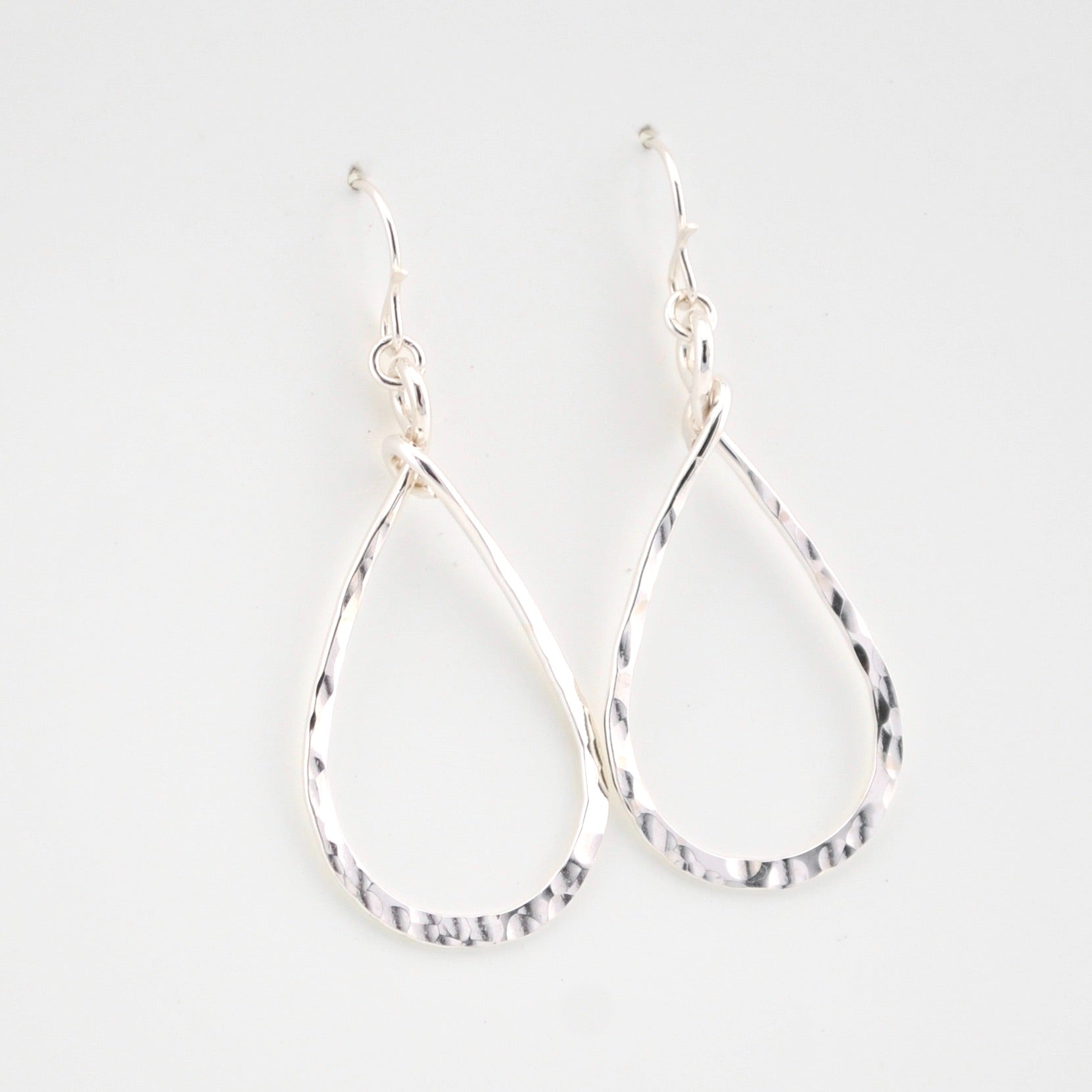 Pair of silver teardrop earrings on a light gray background