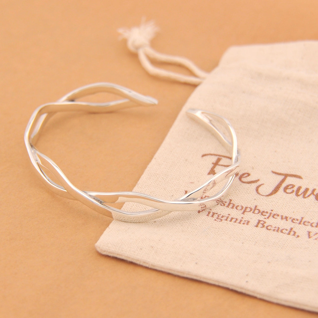 Silver bracelet on a branded jewelry pouch with a beige background